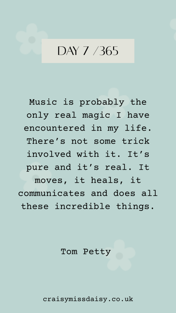 Vertical graphic on a soft blue-green background with daisies for Day 7/365, featuring a typewriter quote by Tom Petty about the magic of music.